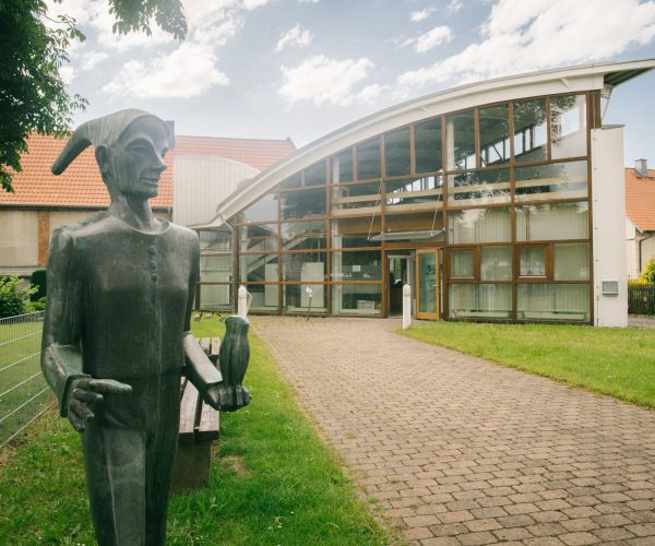 Der Eingang des Till Eulenspiegel-Museum in Schöppenstedt mit einer Bronzeplastik von Till Eulenspiegel, der eine Eule in der Hand hält.